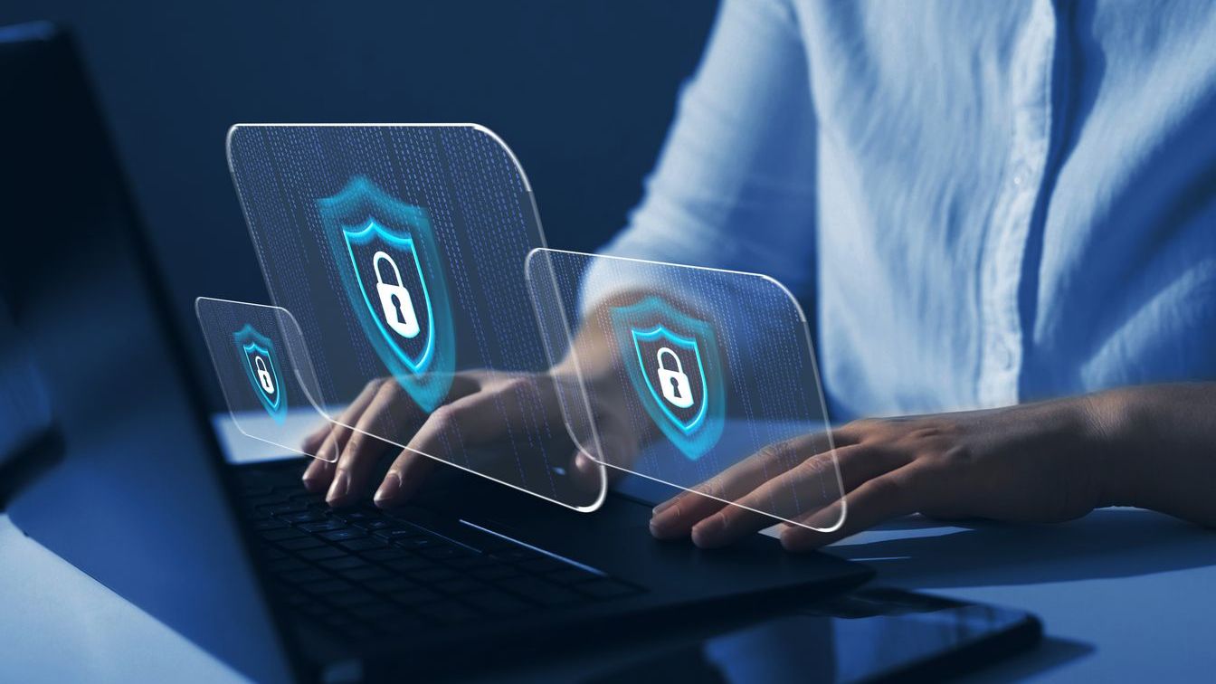 A person typing on a laptop with digital lock icons and shield symbols representing cybersecurity and data protection.