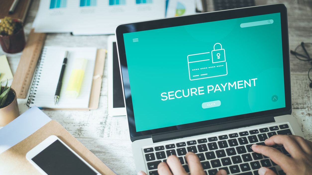 Une personne tapant sur un ordinateur portable affichant un écran de Paiement Sécurisé, mettant en avant la sécurité des transactions en ligne