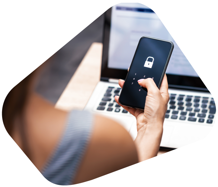 A person entering a passcode on a locked smartphone while using a laptop.