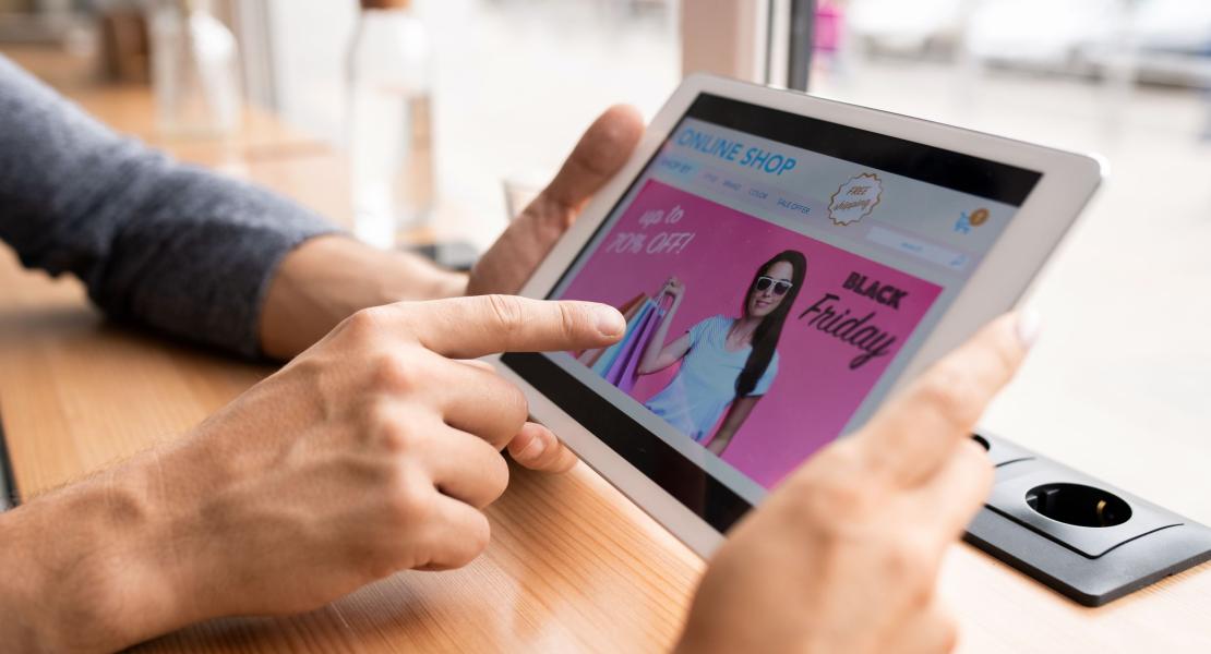 Person browsing a "Black Friday" sale ad on a tablet showing up to 70% off.